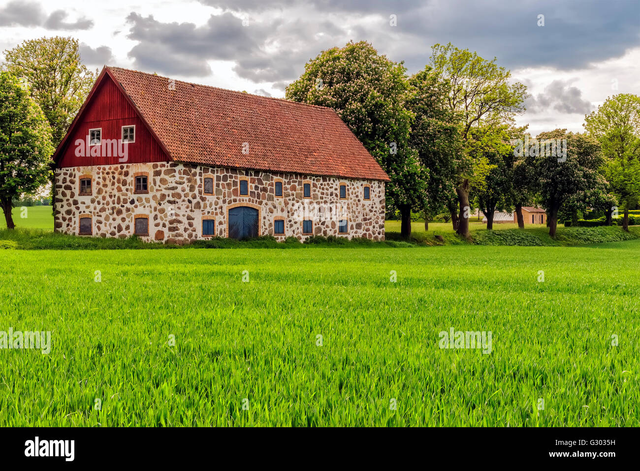 An old stone barn with wooden roof set in the rural countryside of Swedens Skane region. Stock Photo
