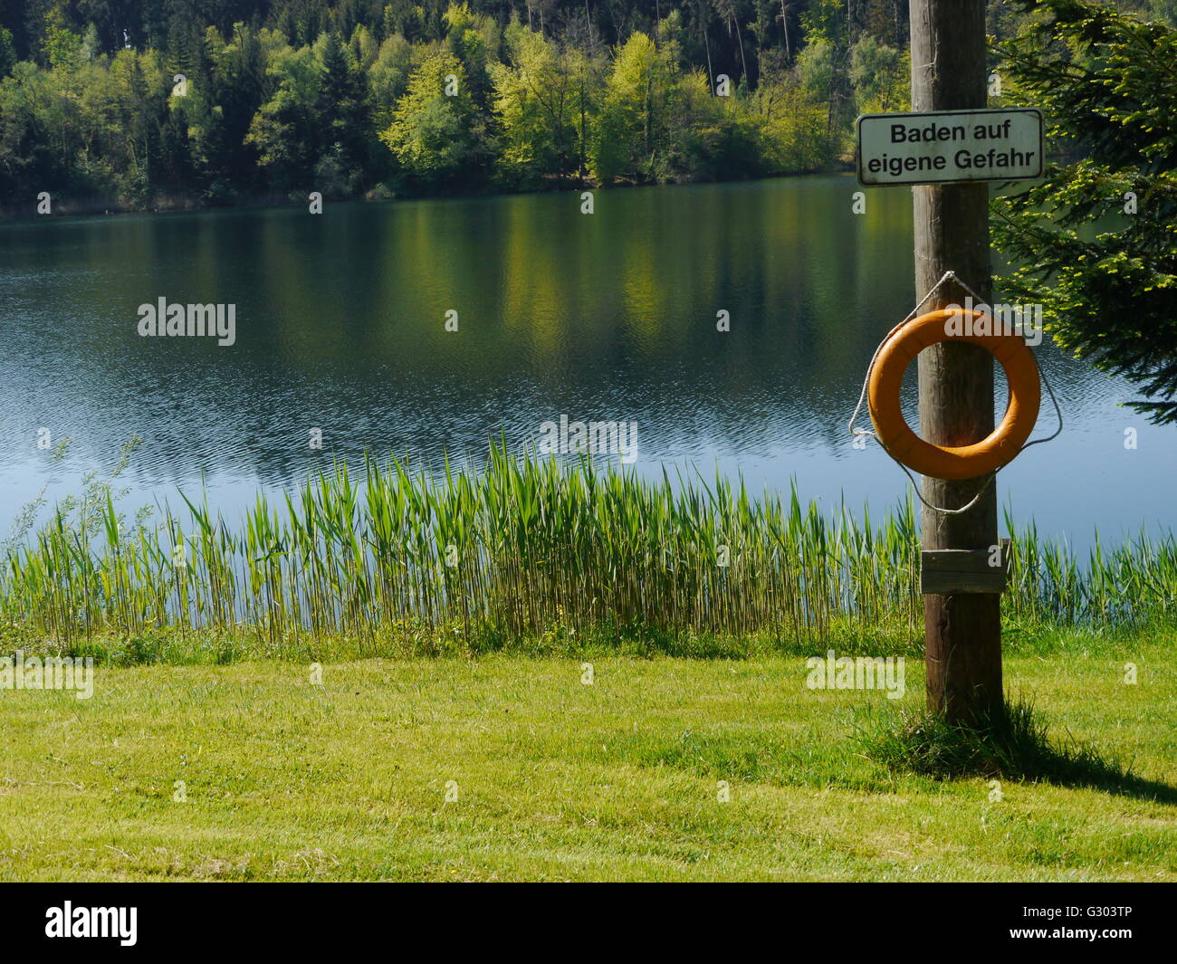 Lifebuoy and sign 'Baden auf eigene Gefahr', German for 'swimming at your own risk', Degersee lake, Baden-Wuerttemberg Stock Photo