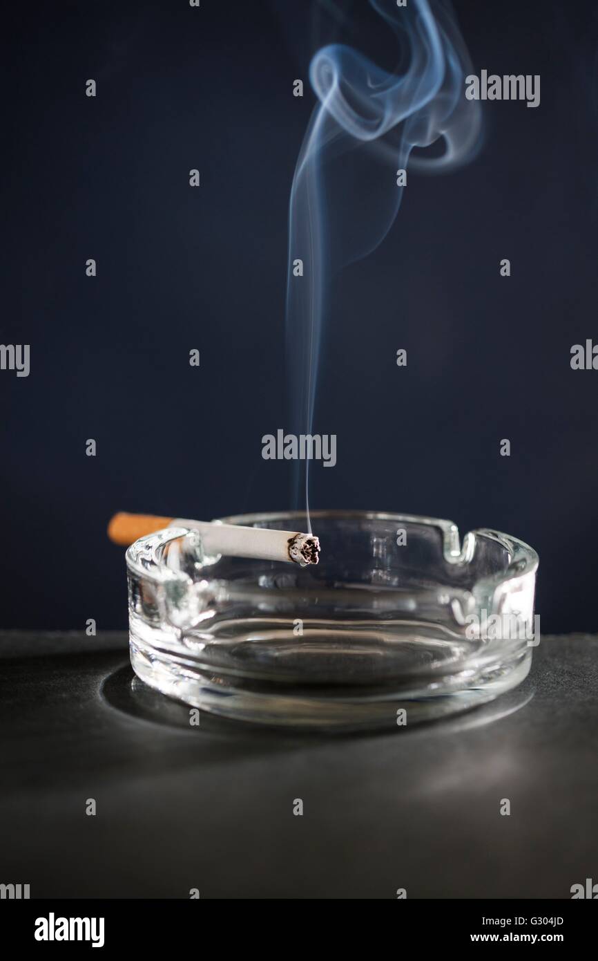Cigarette on ash tray with smoke Stock Photo Alamy