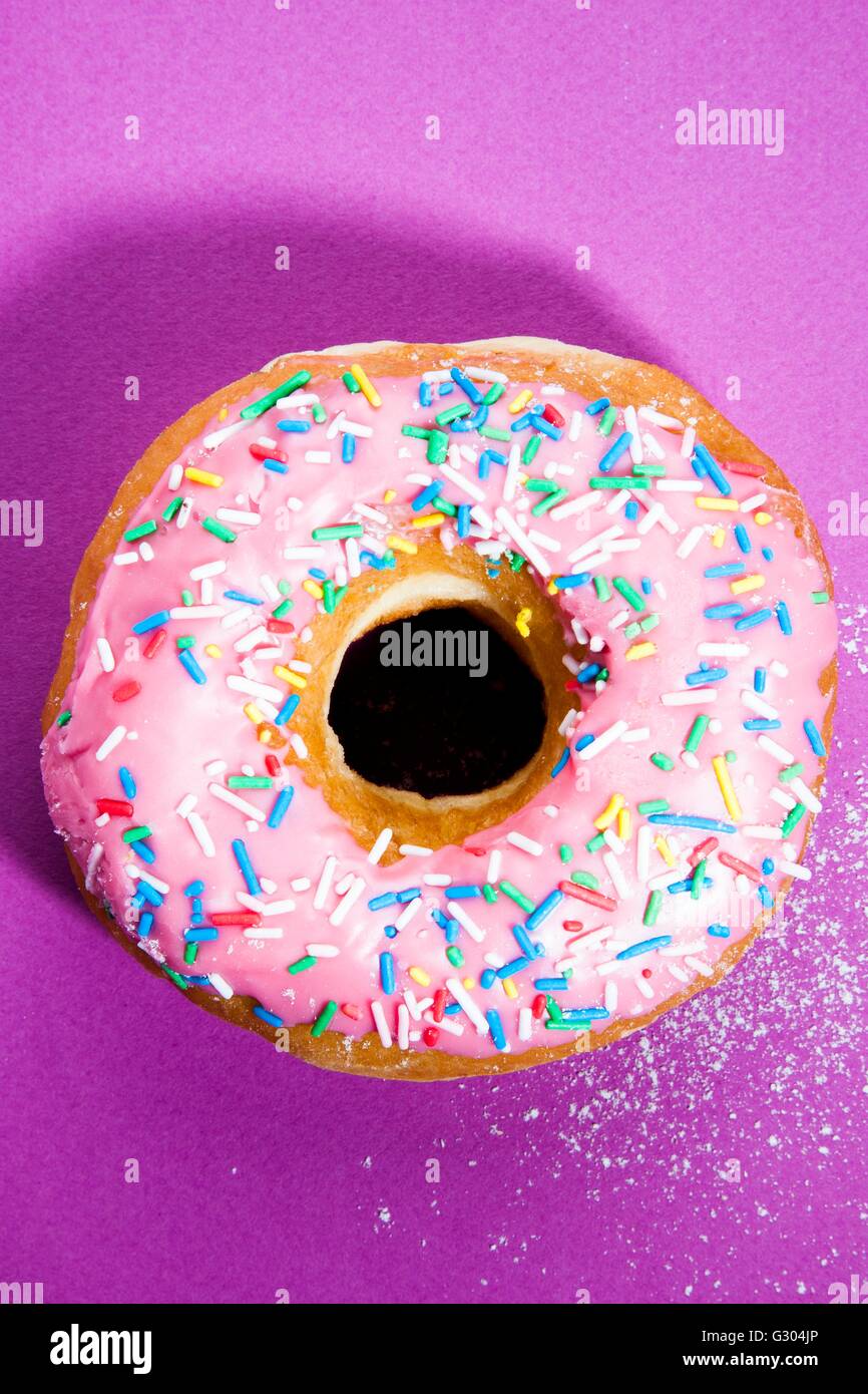 Pink doughnut with sprinkles against a pink background Stock Photo - Alamy