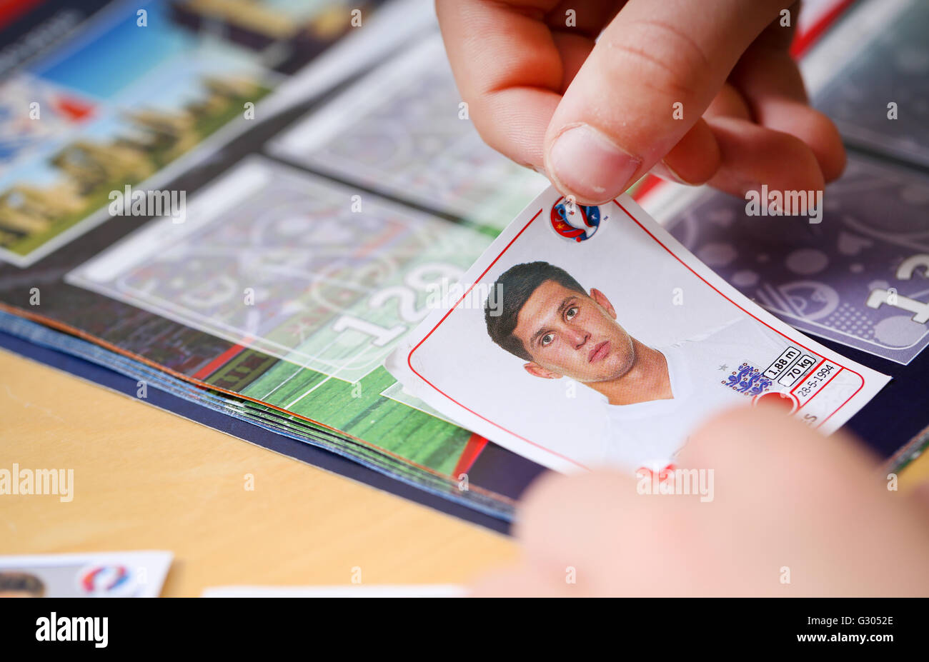 A boy putting Panini football stickers in to an album Stock Photo