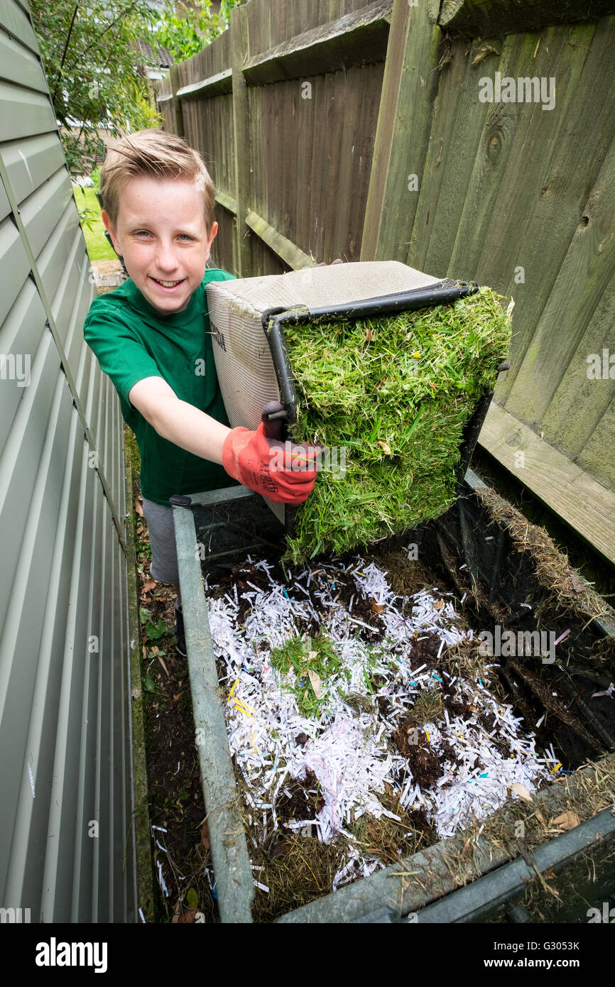 A boy adding grass cuttings to a compost bin Stock Photo