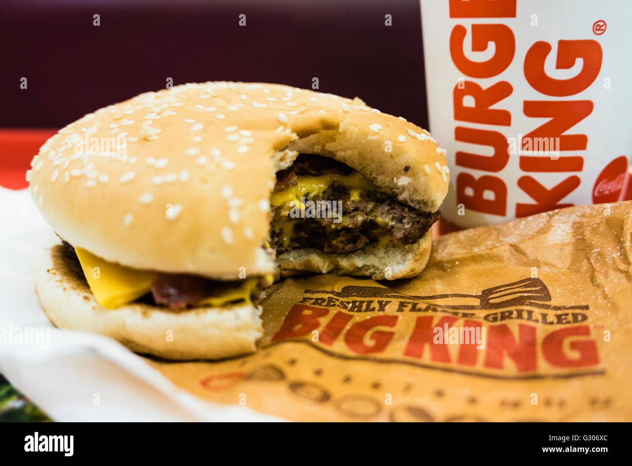 Hamburger, with a bite taken out of it, and drink on a tray in a Burger King fast-food restaurant Stock Photo