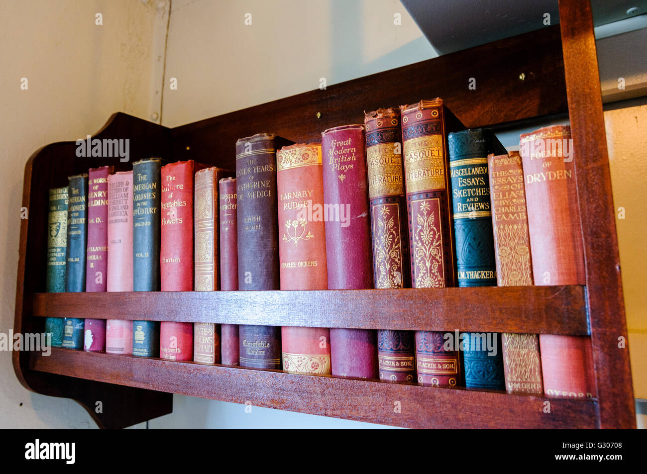 Small bookshelf with old books from around 1900-1915, including English Literature Classics such as Dickens and Thacker. Stock Photo