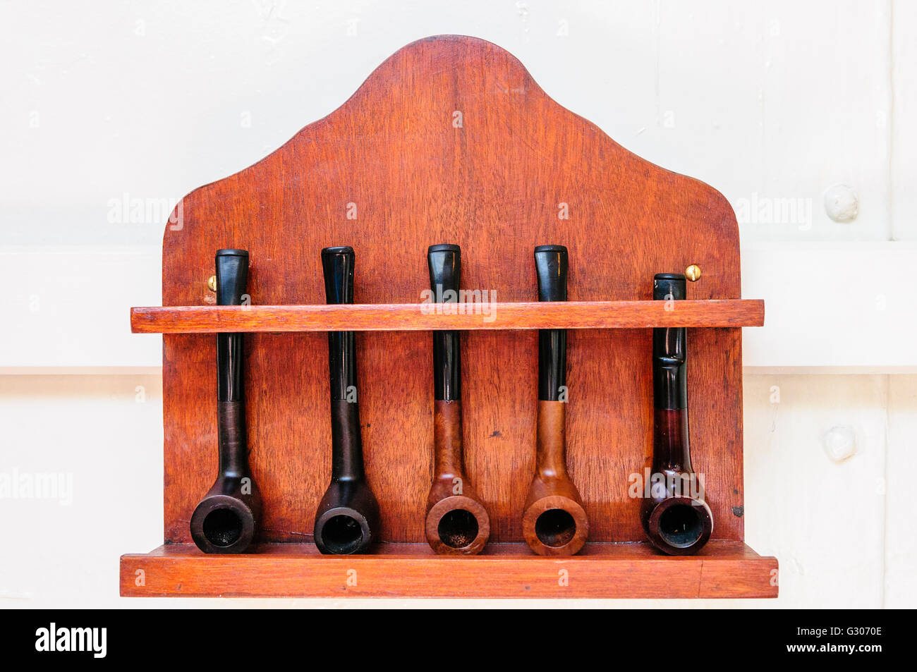 Wooden pipe rack with five pipes. Stock Photo