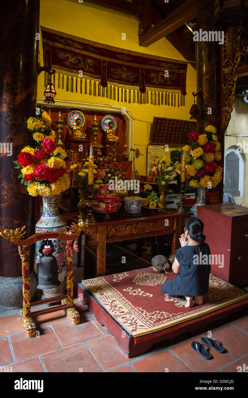 A woman praying in the Bach Ma Temple, Hanoi, Vietnam. Stock Photo