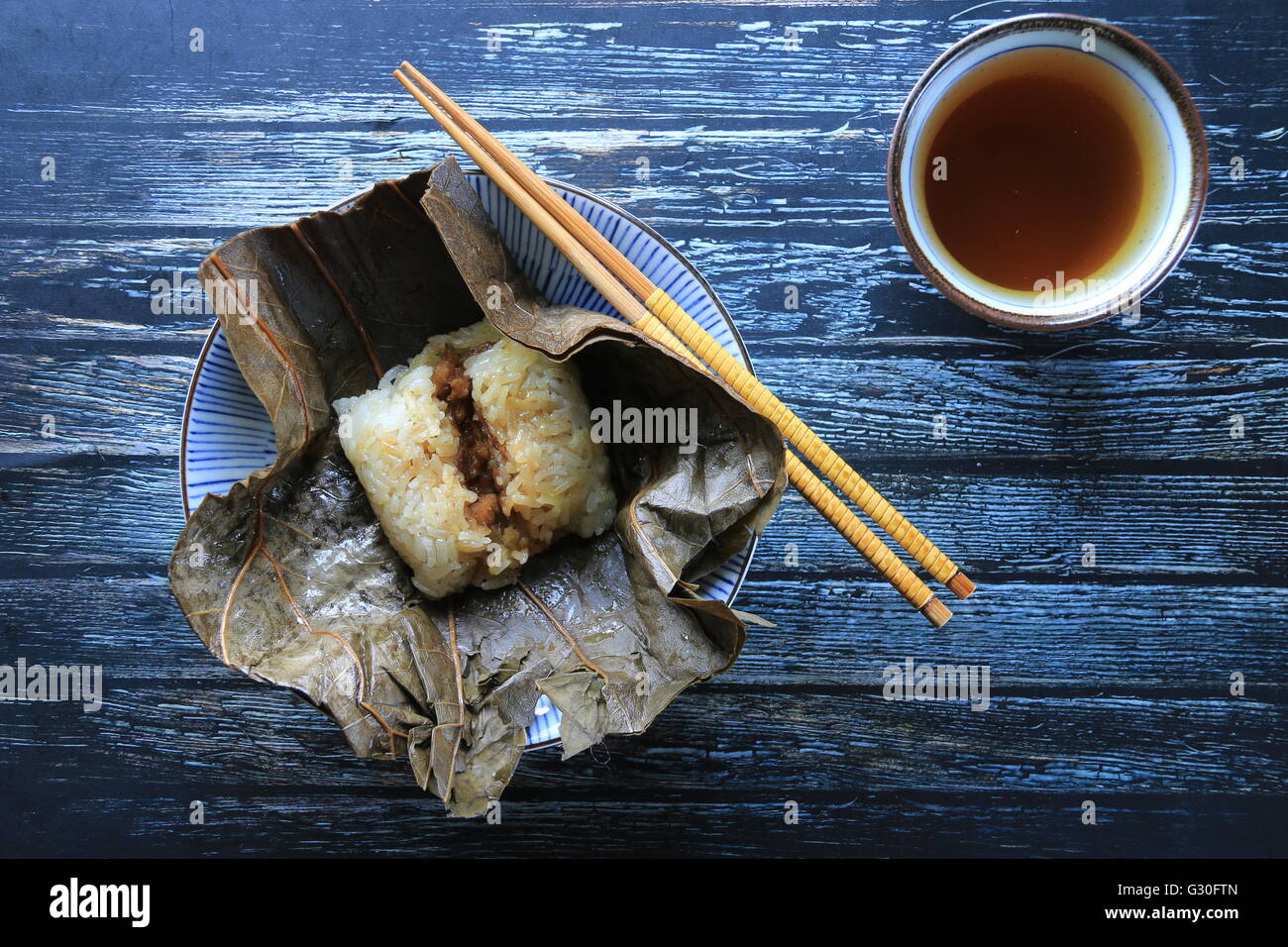 Lo Mai Gai. Steamed parcel of sticky rice with pork, shrimp, and egg in lotus leaf. Flat-lay view. Stock Photo