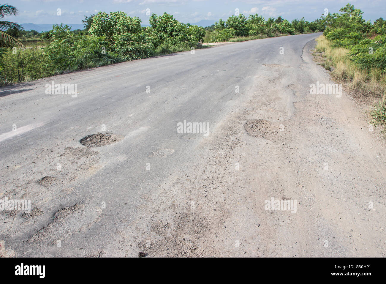 Damaged road in the countryside, damaged asphalt road with potholes caused, Poor road. Stock Photo