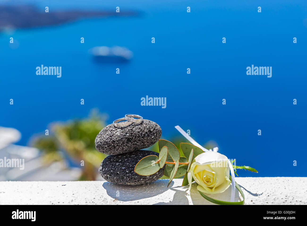 Wedding rings on stones and rose, on sea background Stock Photo - Alamy