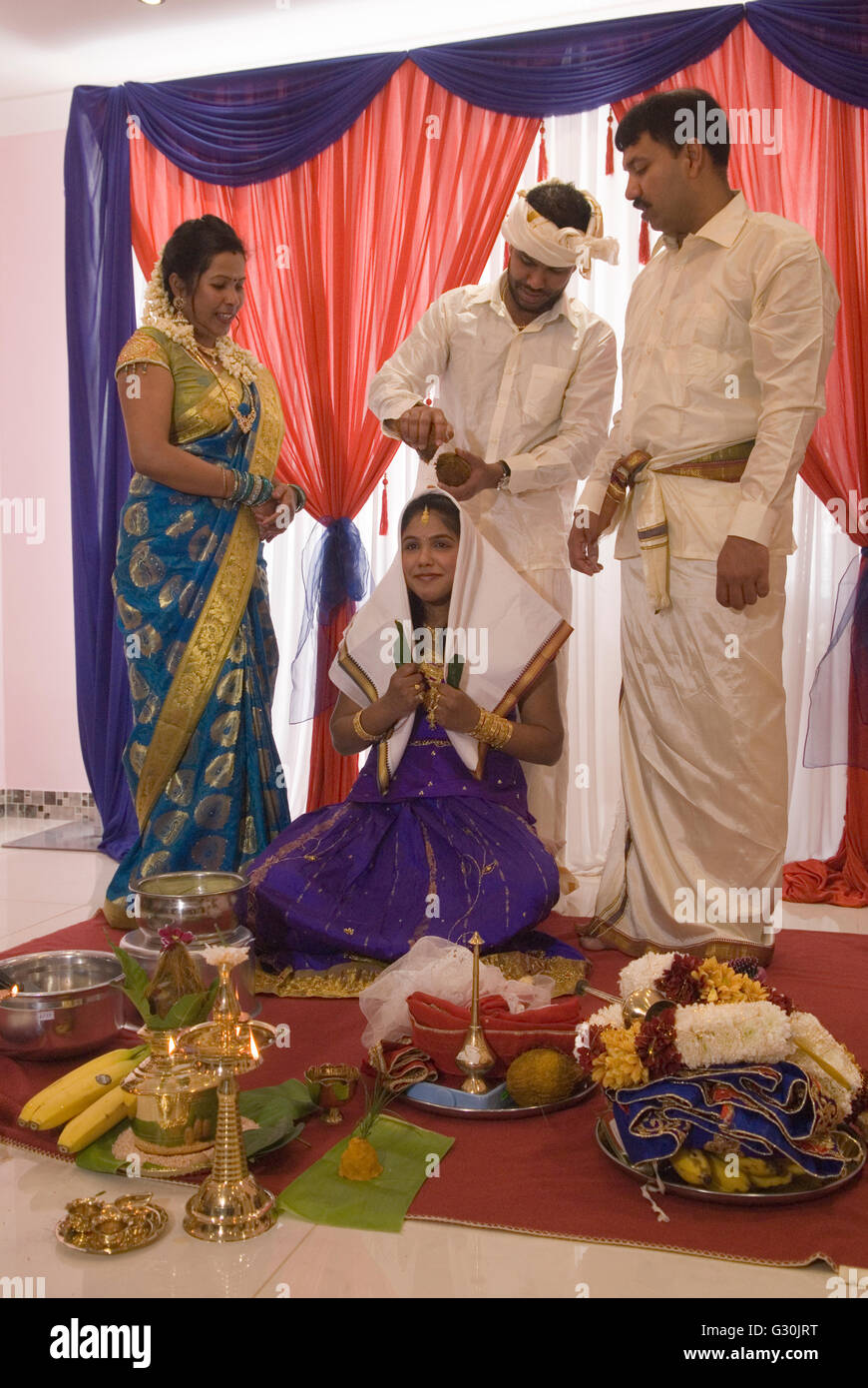 Hindu family in London UK celebrate their 16 year old daughters coming of age party. Ritushuddhi,  also called as Ritu Kala Samskara, Coconut milk is poured onto her head by her brother. It  symbolises health and prosperity, family members stand by her side. Mitcham south London. A celebration and the transition to womanhood.   2010s 2016 UK  HOMER SYKES Stock Photo