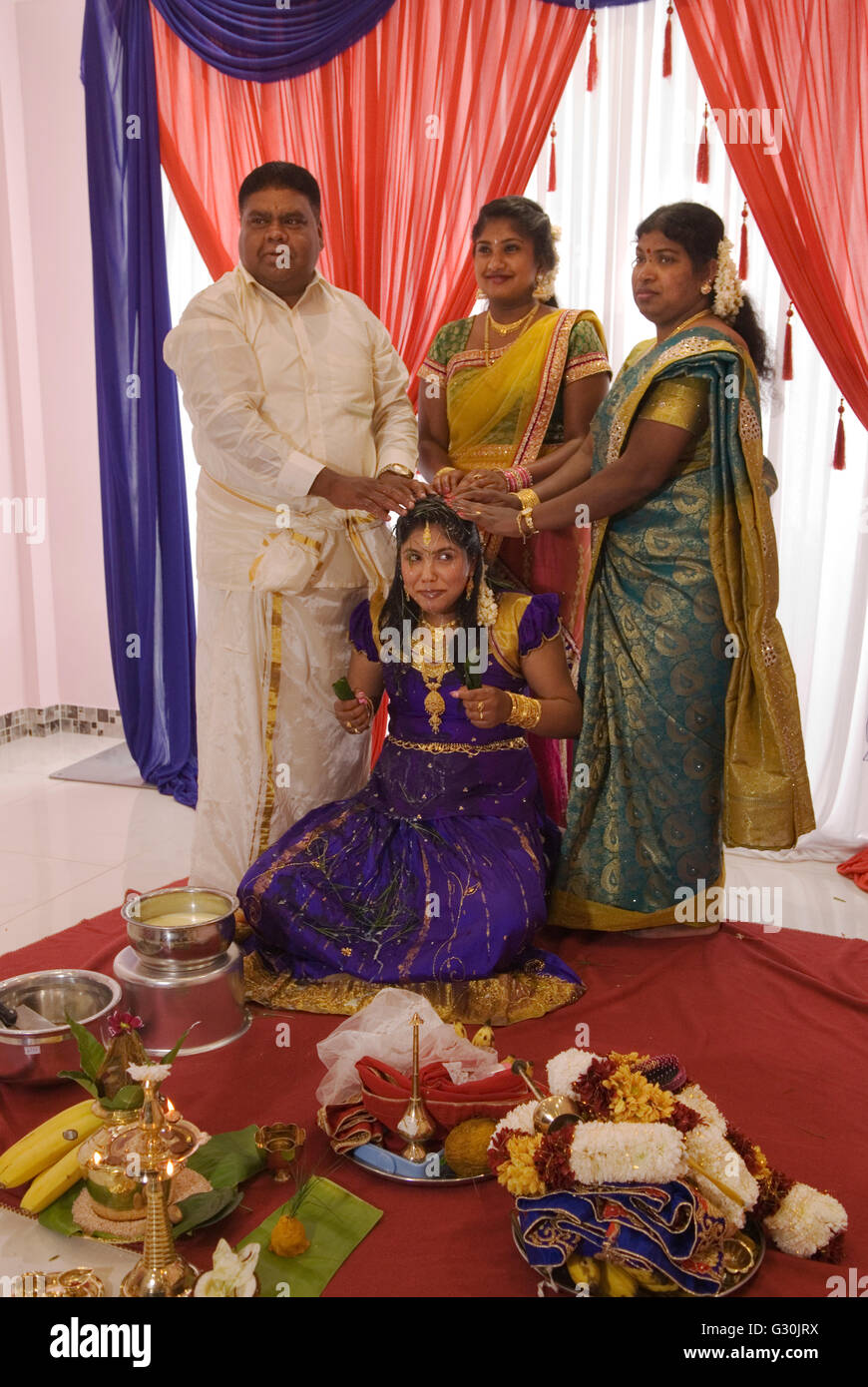 Hindu family in London celebrate their 16 year old daughters coming of age party. Ritushuddhi, also called as Ritu Kala Samskara, Coconut milk is poured onto her head by her brother. It  symbolises health and prosperity, family members stand by her side. Mitcham south London. A celebration and the transition to womanhood.   2010s 2016 UK  HOMER SYKES Stock Photo