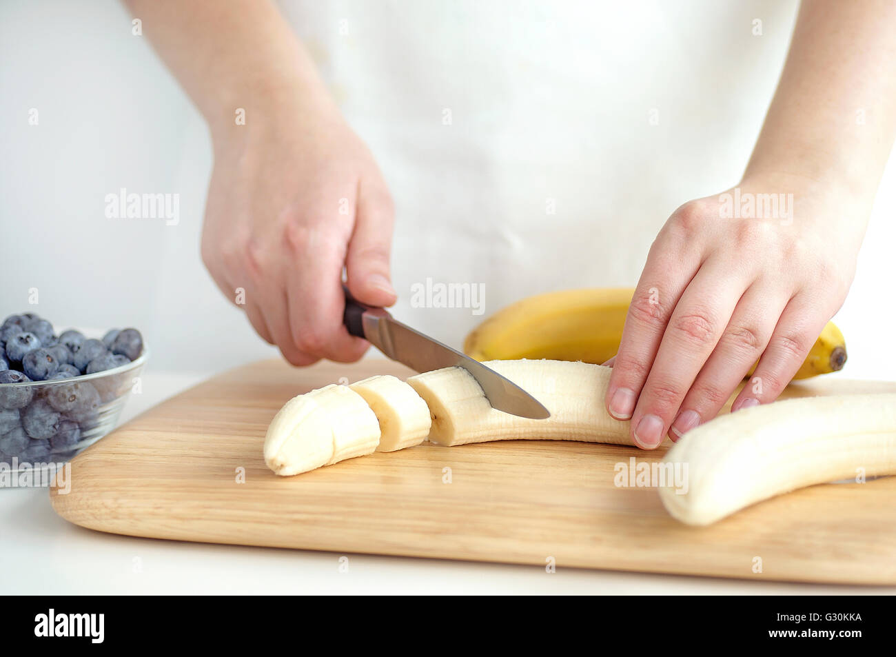Woman slicing banana on wooden chopping board Stock Photo Alamy