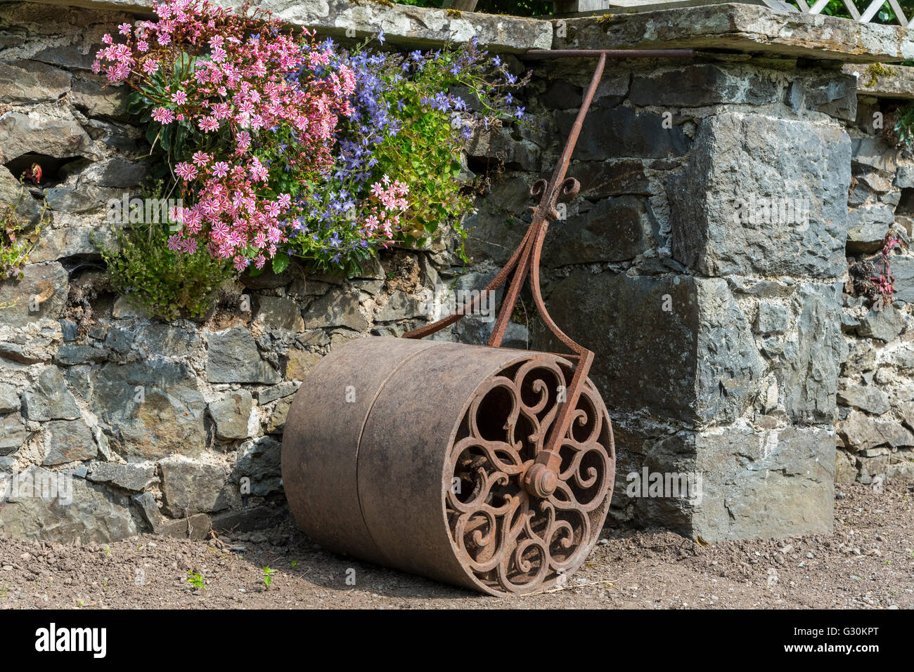 Victorian garden roller against a stone wall. Wrought iron. Stock Photo