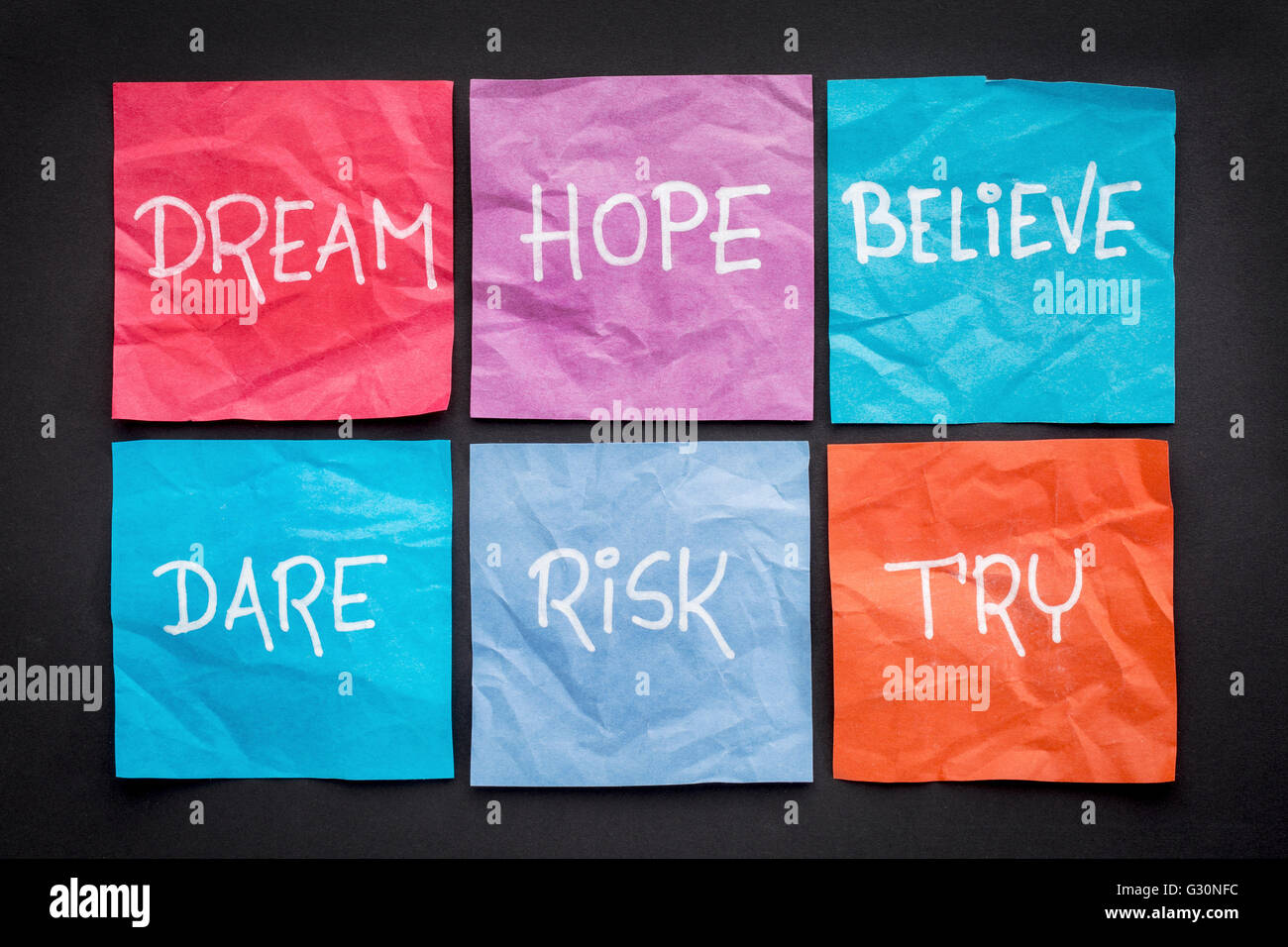 dream, hope, believe, dare, risk, and try - motivational concept - a set of crumpled sticky notes with white handwritten text ag Stock Photo