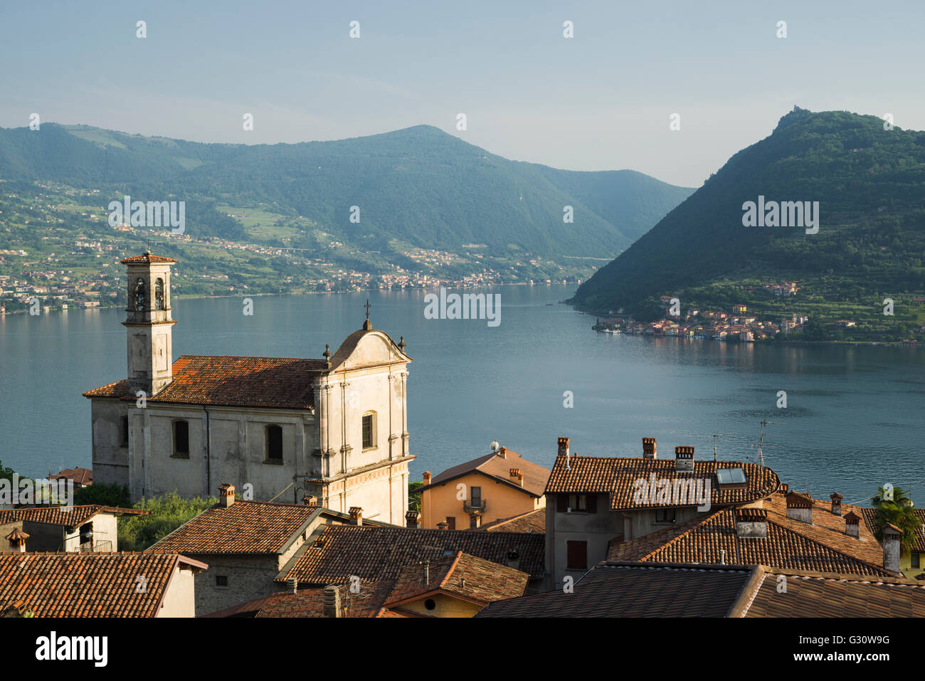 Church of San Rocco in Marone village with panorama of Lake Iseo and Monte Isola island in the evening light, Lombardy, Italy Stock Photo