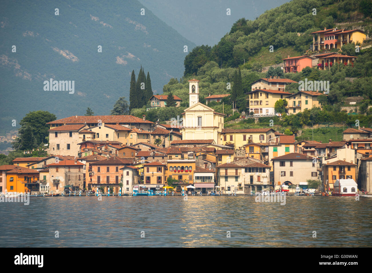 Colorful houses of Peschiera Maraglio on wooded mountain slopes on the shores of the island Monte Isola on Lake Iseo,Italy Stock Photo