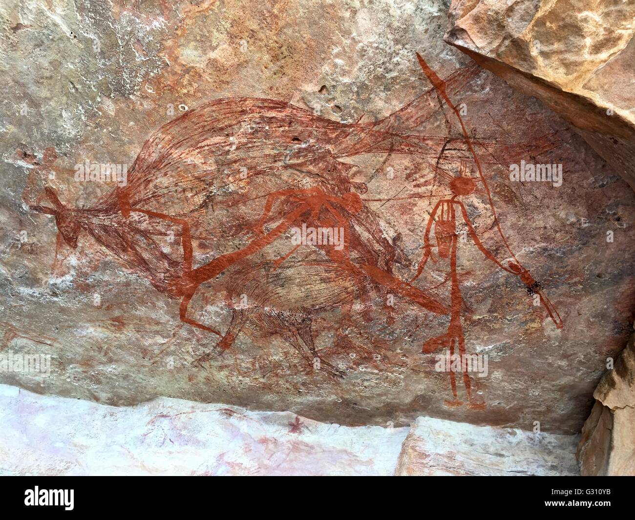A rock wallaby with human figures painted in a cave at 'The Castle' at Gubara in Kakadu National Park, Australia. Stock Photo