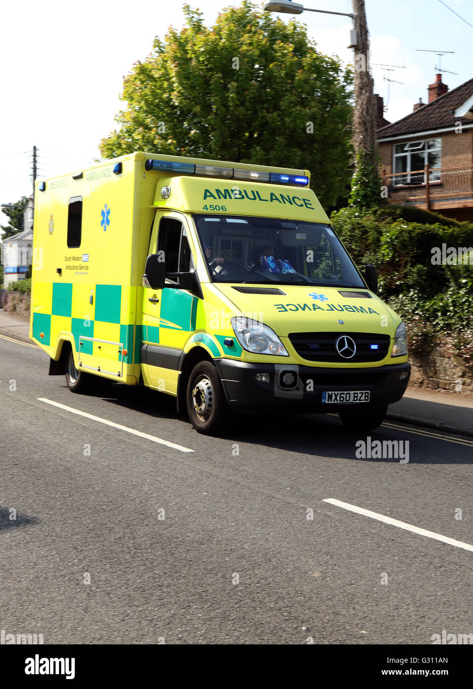 Yellow British ambulance on a blue light run through the village of Cheddar heading for the gorge. May 2016 Stock Photo