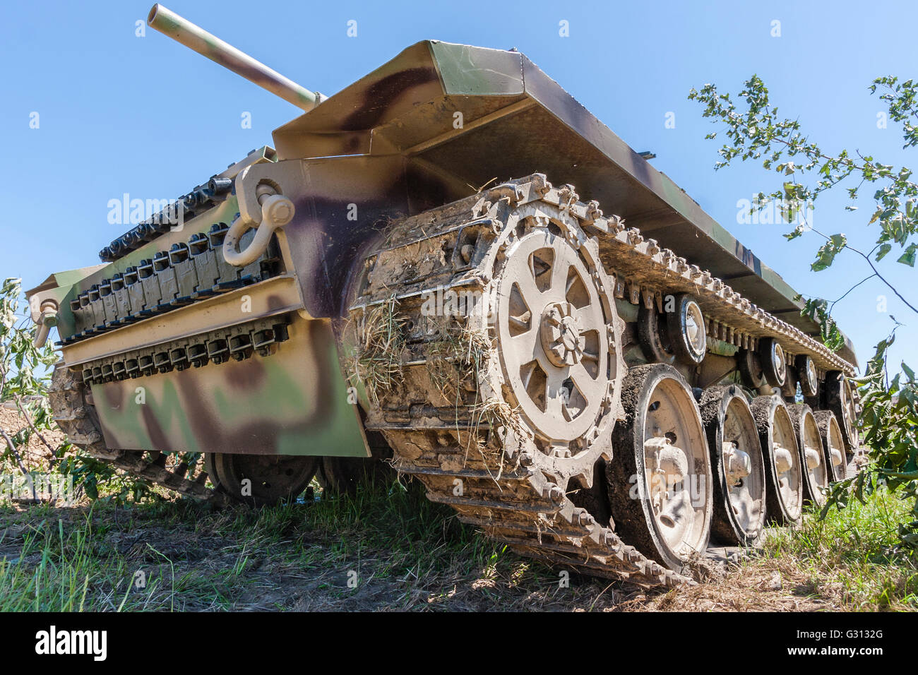 World War Two living history. German tank, Panzer IV, close up wide angle shot from front side below tracks, tank towering over viewer, blue sky above. Stock Photo