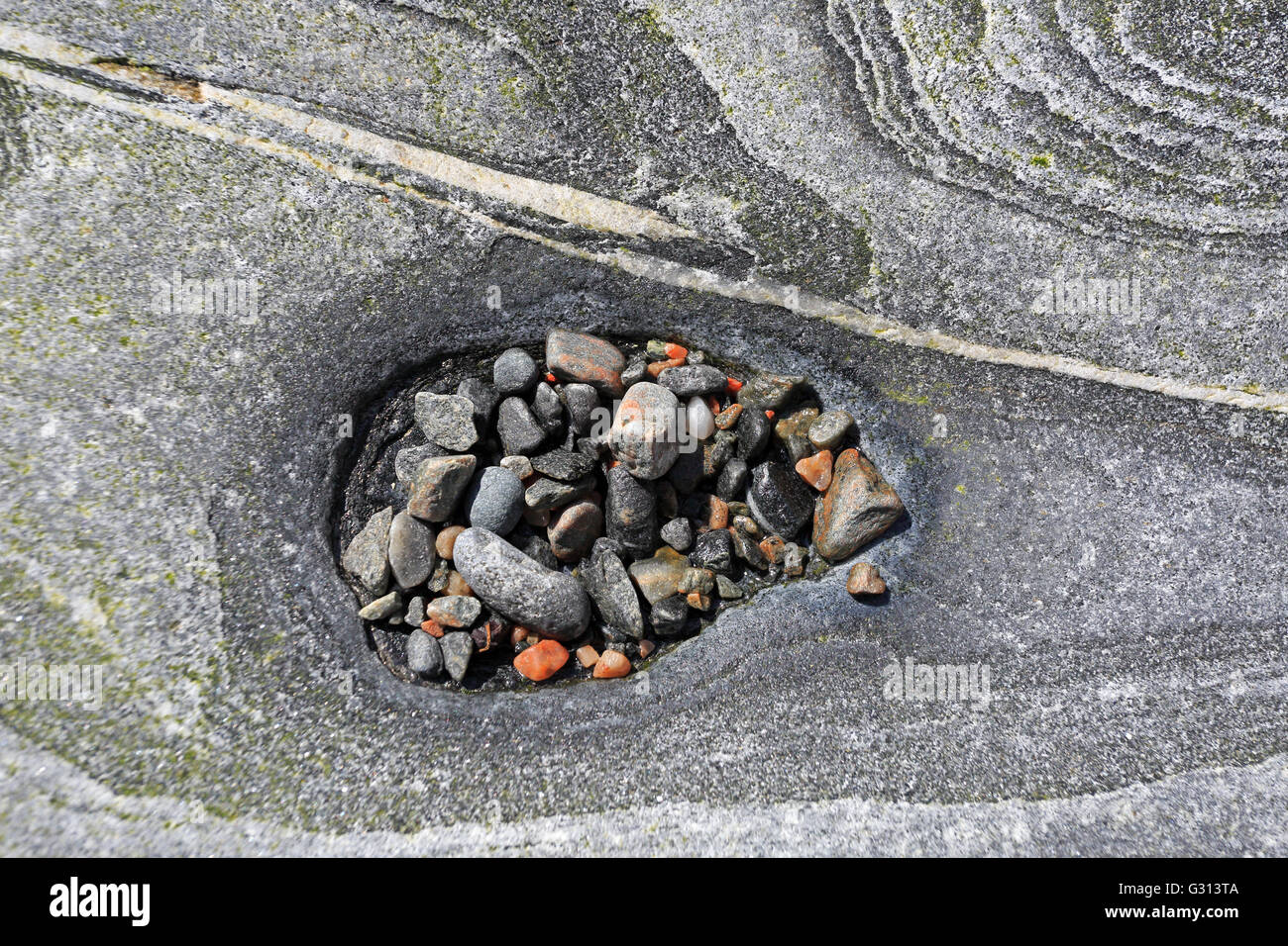 Small hole in a rock filled with colourful pebbles on the Island of Taransay in the Outer Hebrides Stock Photo