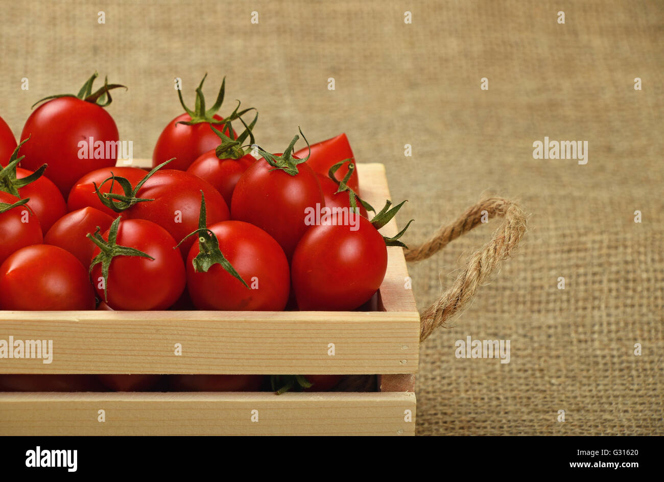 Red ripe fresh cherry tomatoes in small wooden box with twine jute ...