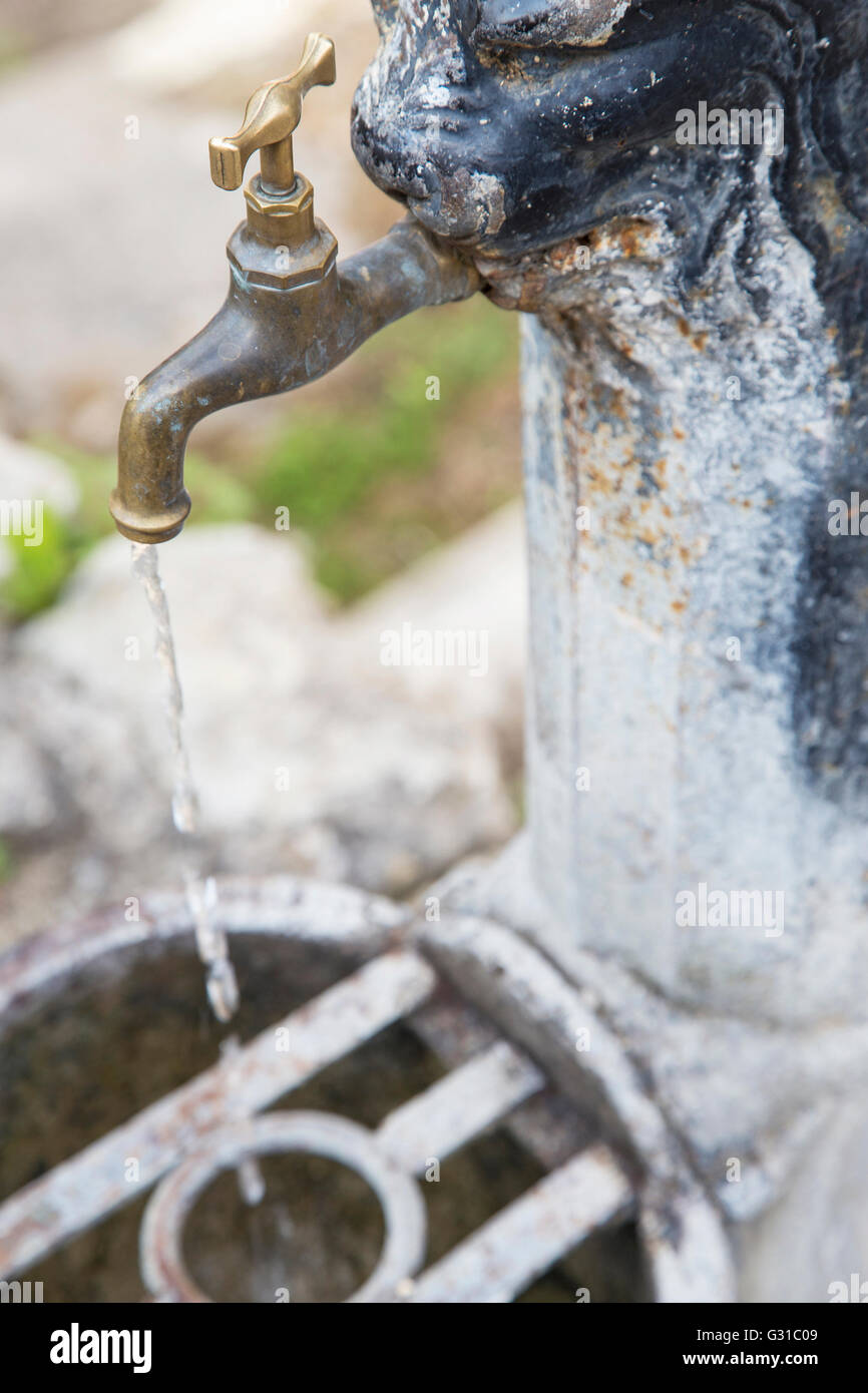 Iron rusty faucet with with water flowing. Potable drinking water is an invaluable resource. Today 1.8 billion people still use Stock Photo