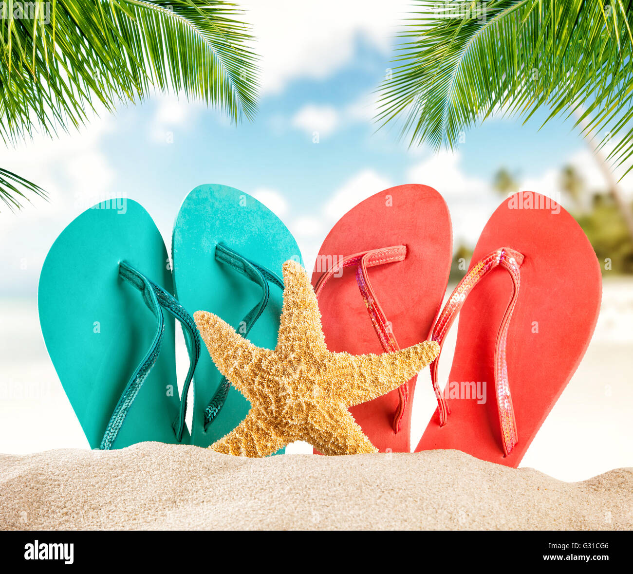 Summer flipflops on sandy beach, blur sea on background. Summer exotic