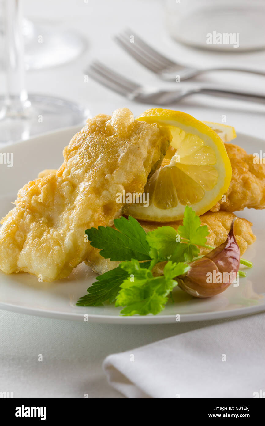 Battered fried hake with lemon and parsley. Stock Photo