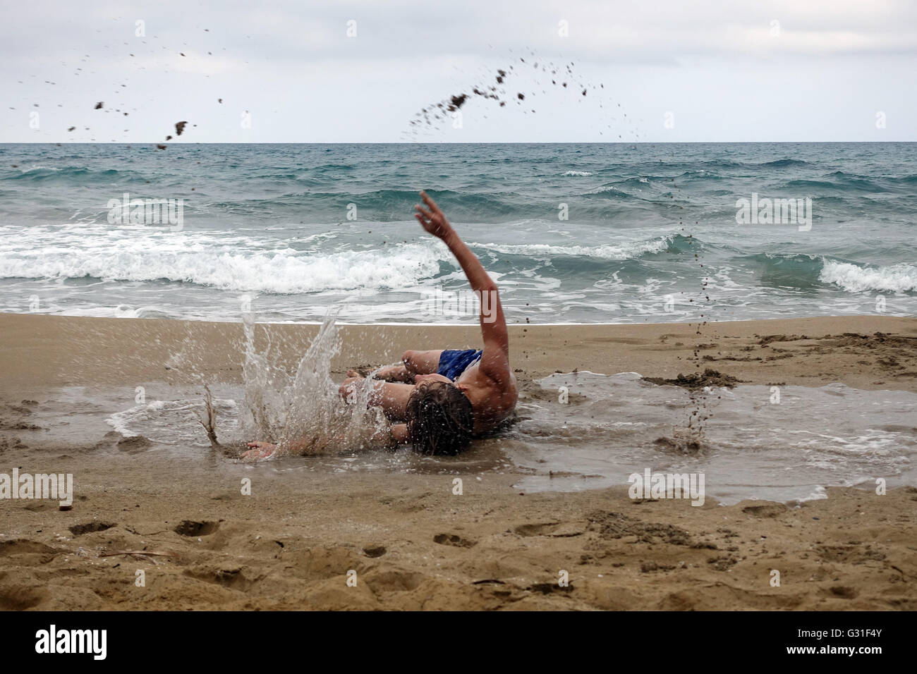 Noto, Italy, Young feels himself on the beach of Calamosche in a puddle Stock Photo