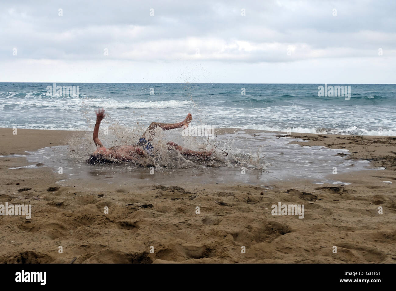 Noto, Italy, Young feels himself on the beach of Calamosche in a puddle Stock Photo