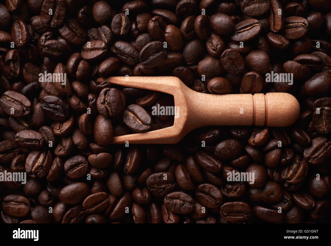 Food ingredients: wooden scoop and dark roasted coffee beans arranged as flat background Stock Photo
