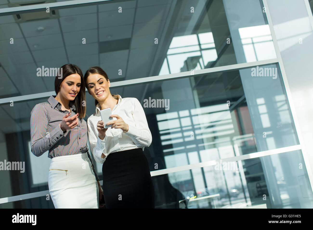 Two businesswomen standing together with the mobile phone Stock Photo