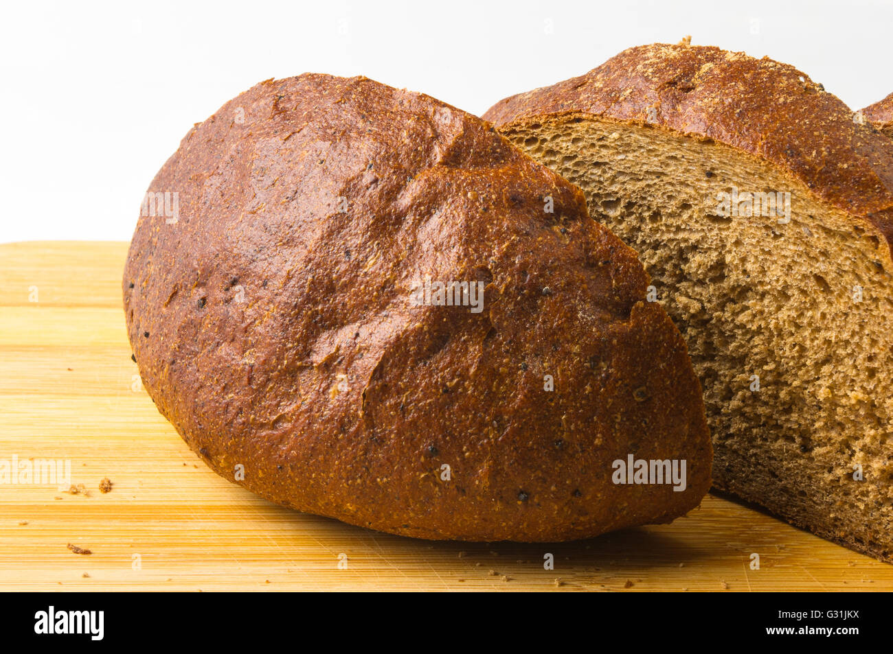 Sliced dark bread with crumbs on wood board Stock Photo