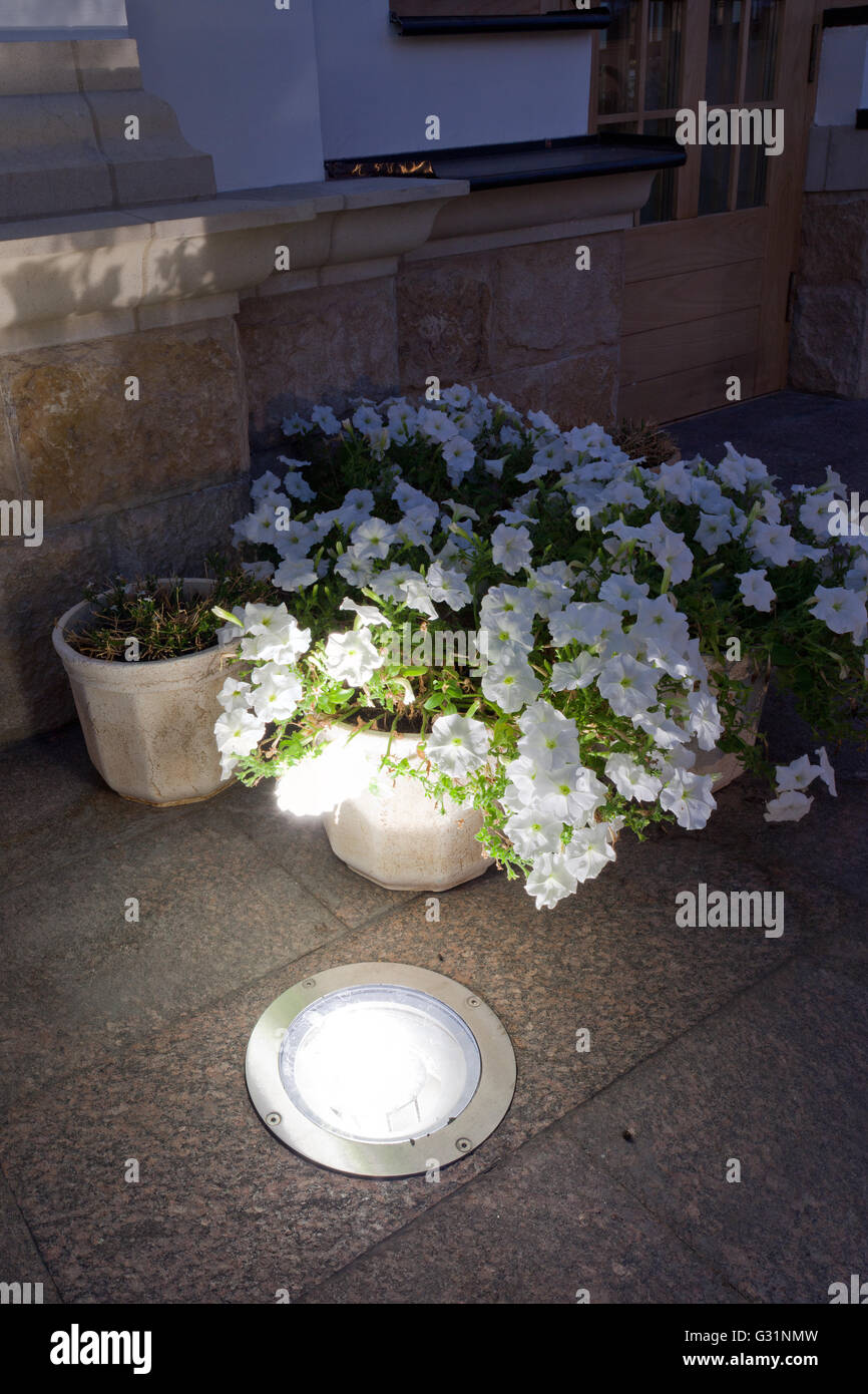 The built-in light in the granite sidewalk next to flower bed Stock Photo