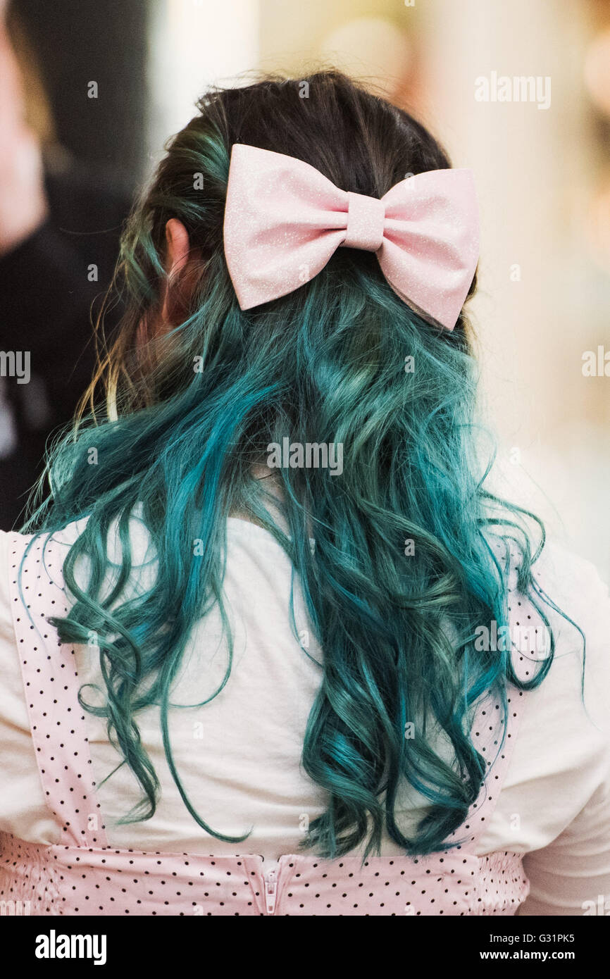 A woman from behind with a pink bow in dyed green hair at a vintage fayre. Stock Photo