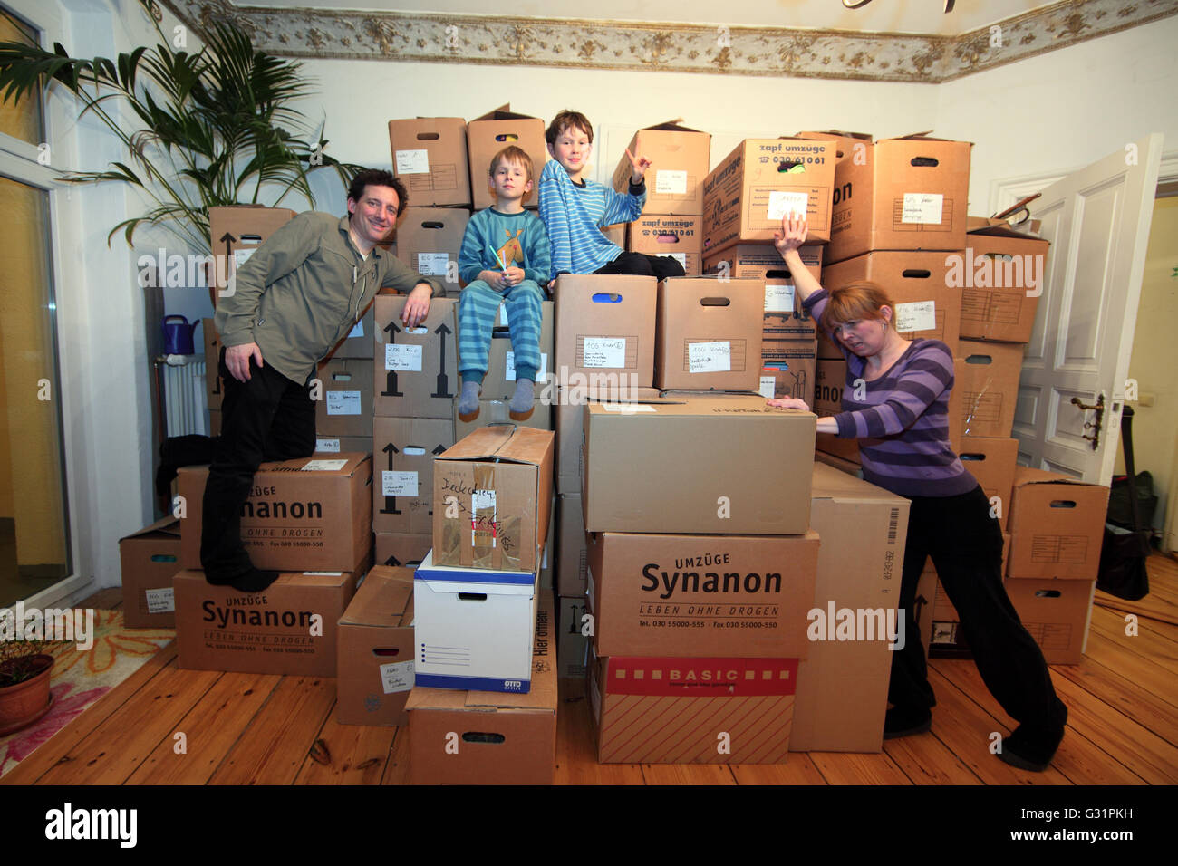 Berlin, Germany, family posing in front froehlich stacked moving boxes Stock Photo