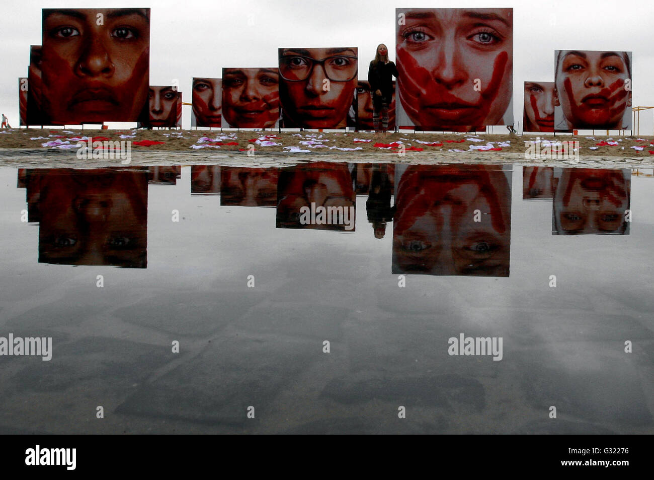 Rio De Janeiro, Brazil. 6th June, 2016. A woman poses in front of images of women displayed during a protest against the abuses to women, at Copacabana Beach, in Rio de Janeiro, Brazil, on June 6, 2016. Credit:  Severino Silva/AGENCIA ESTADO/Xinhua/Alamy Live News Stock Photo