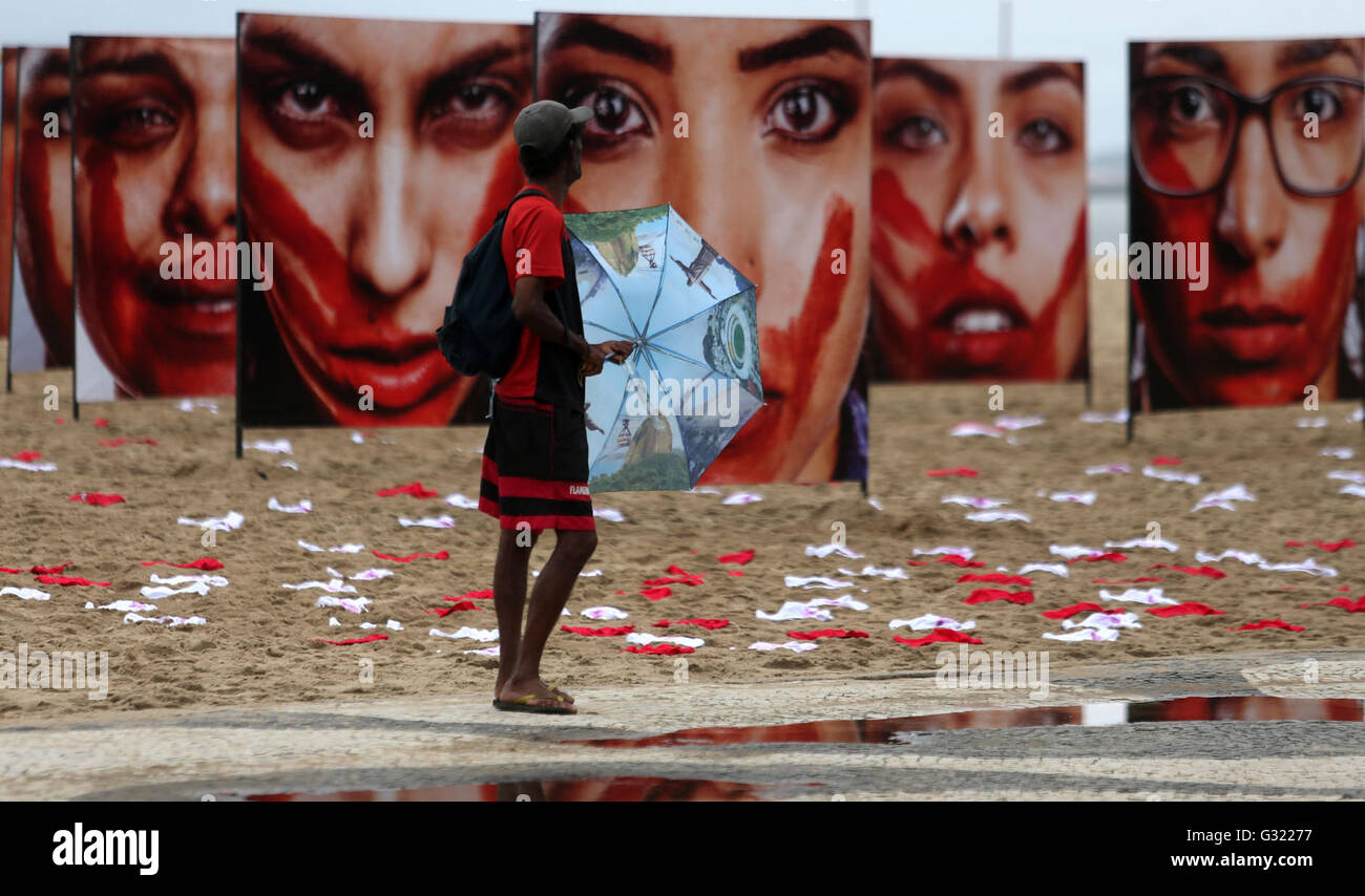 Rio De Janeiro, Brazil. 6th June, 2016. A person walks in front of images of women displayed during a protest against the abuses to women, at Copacabana Beach, in Rio de Janeiro, Brazil, on June 6, 2016. Credit:  Fabio Motta/AGENCIA ESTADO/Xinhua/Alamy Live News Stock Photo