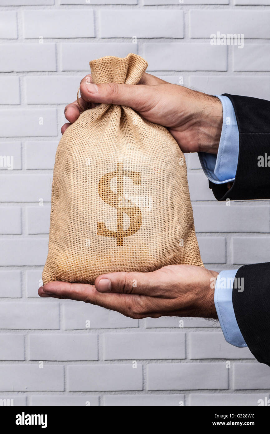 Hands holding a sack of money and white brick background Stock Photo ...