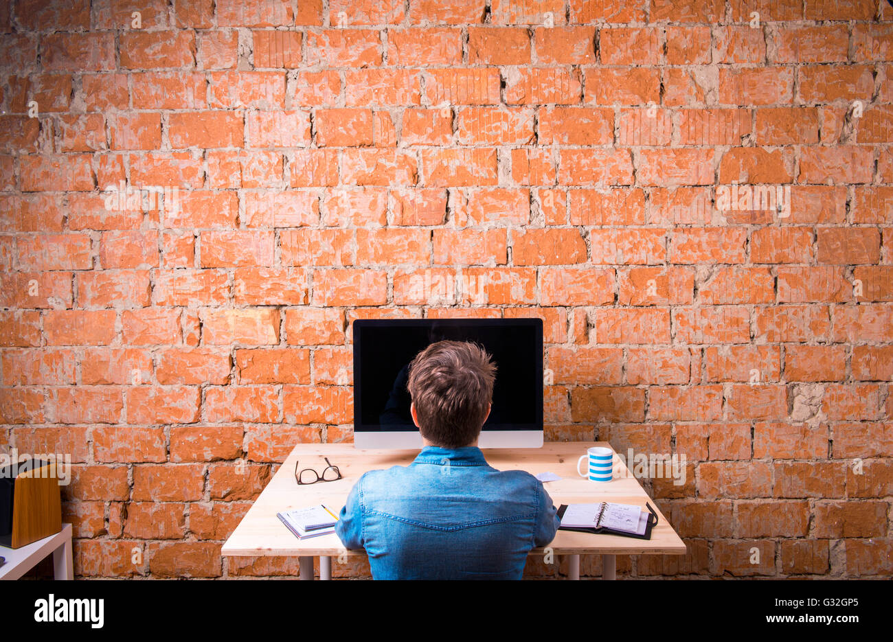 Business person sitting at office desk working, rear view Stock Photo ...