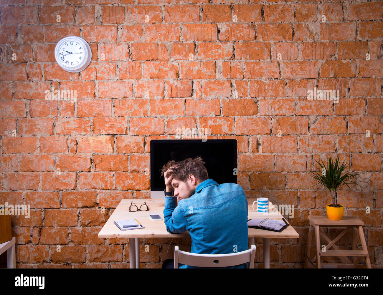 Sad businessman sitting at office desk, rear view Stock Photo - Alamy