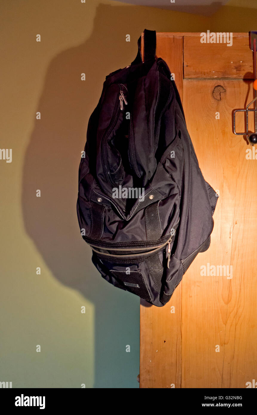 A backpack hanging on the corner of a door resembles an evil face Stock Photo