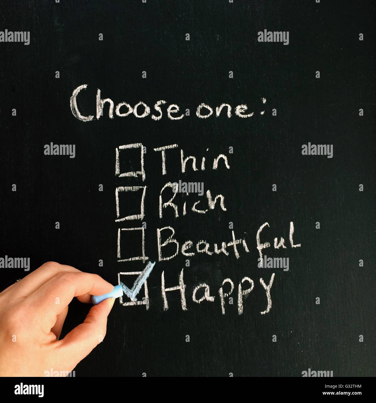 Hand writing List of choices on blackboard: thin, rich, beautiful, happy Stock Photo