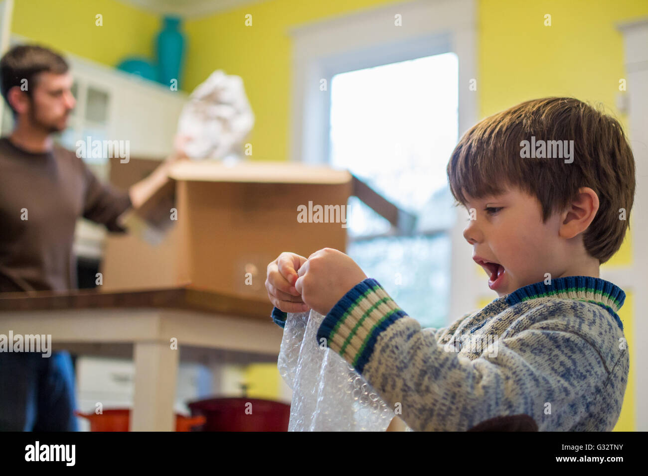 Boy playing with bubble wrap with father packing Stock Photo Alamy