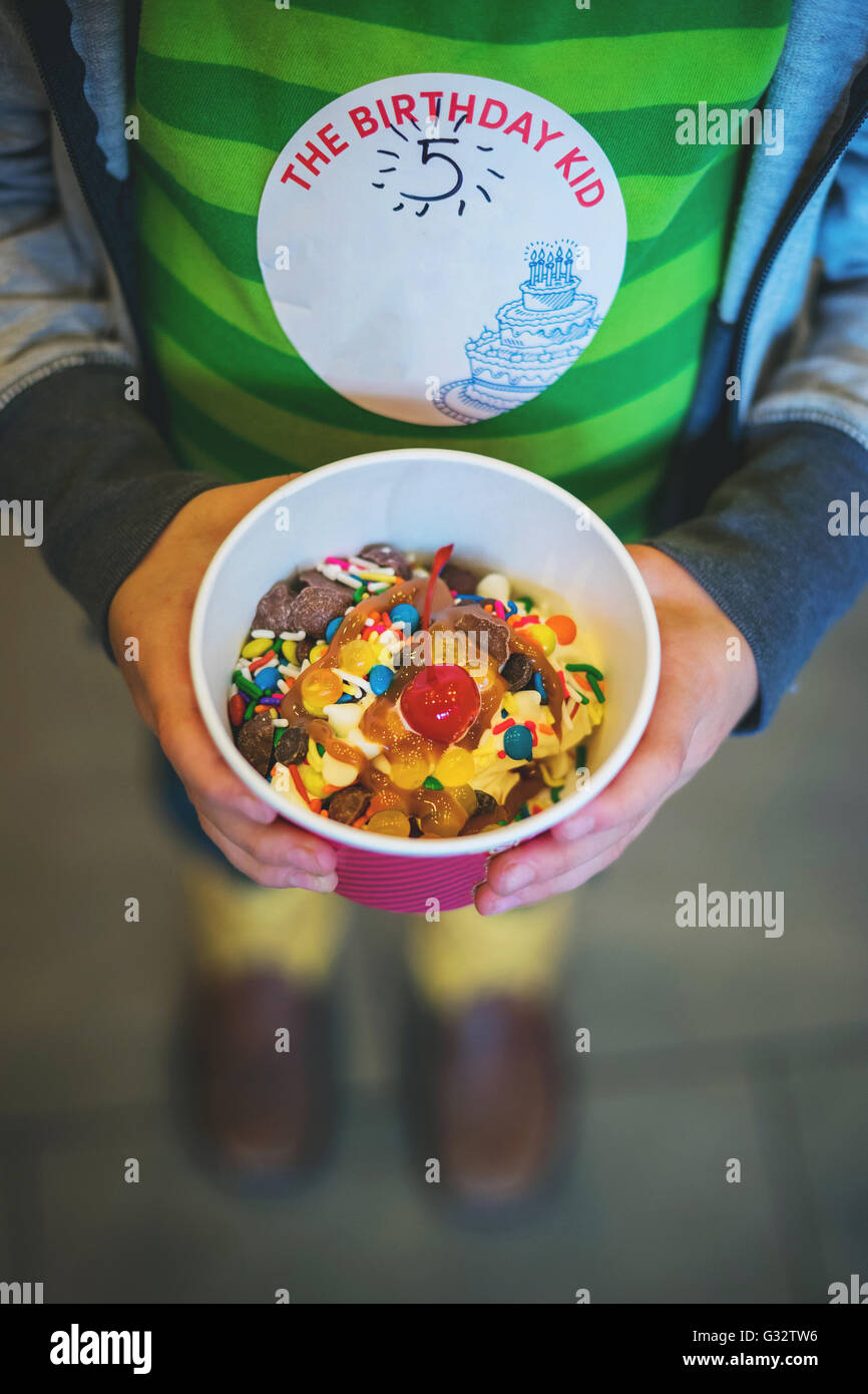 Boy holding tub of frozen yogurt with sprinkles Stock Photo
