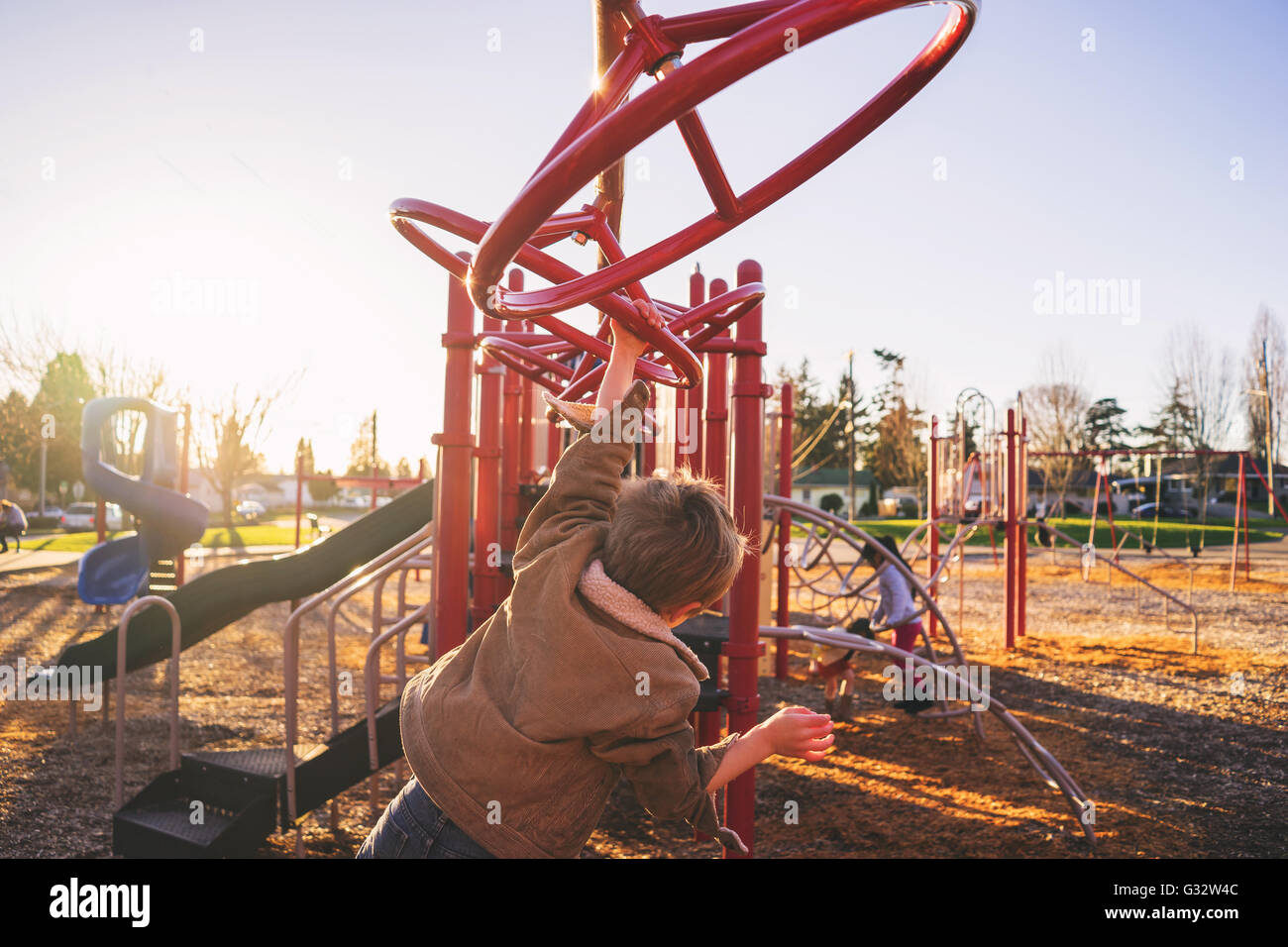 Rear view of boy swinging on monkey bars in playground Stock Photo
