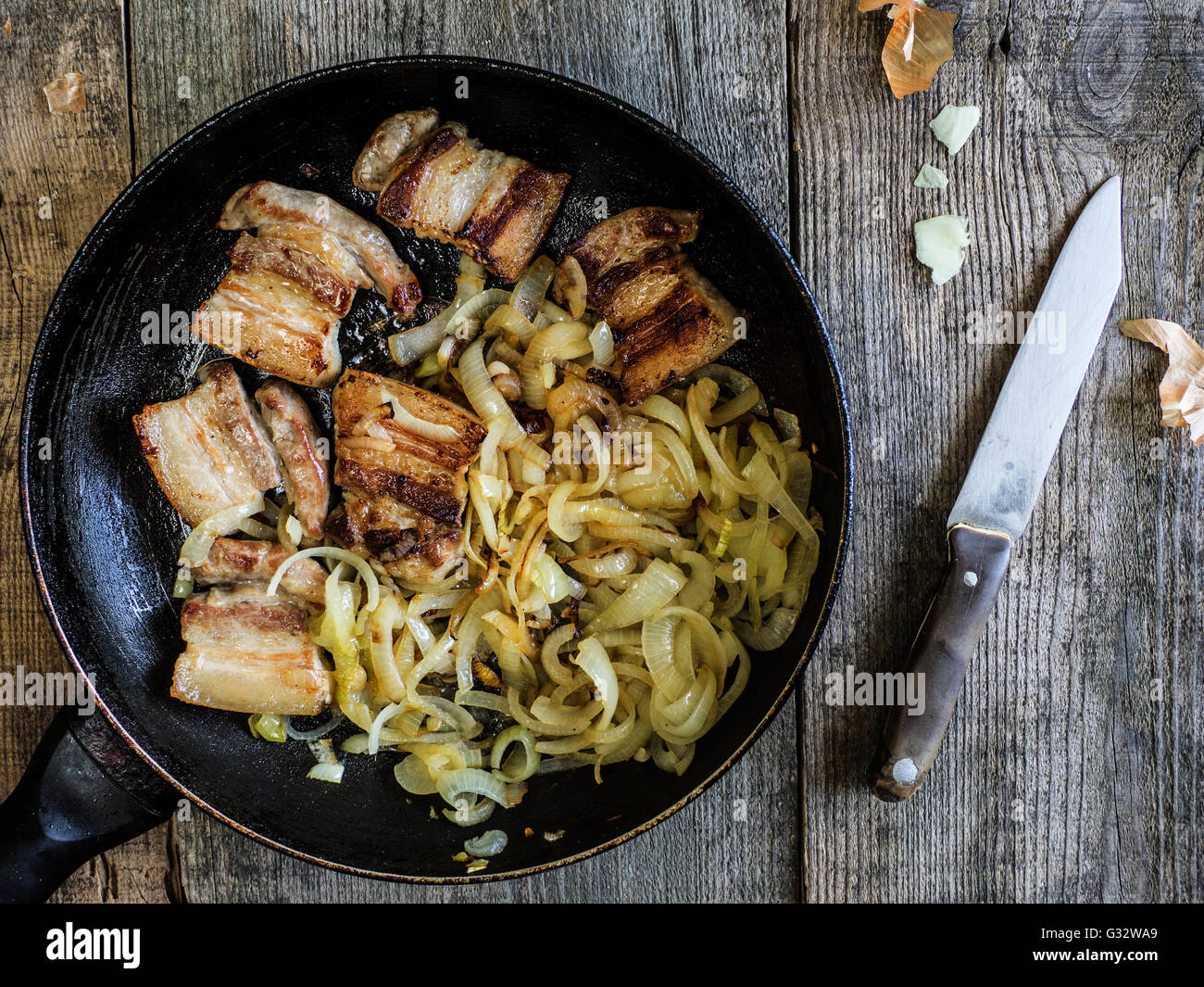 bacon fried with onions in frying pan Stock Photo