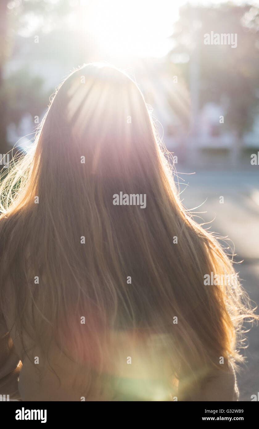 Rear view of woman walking down street in sunlight Stock Photo - Alamy