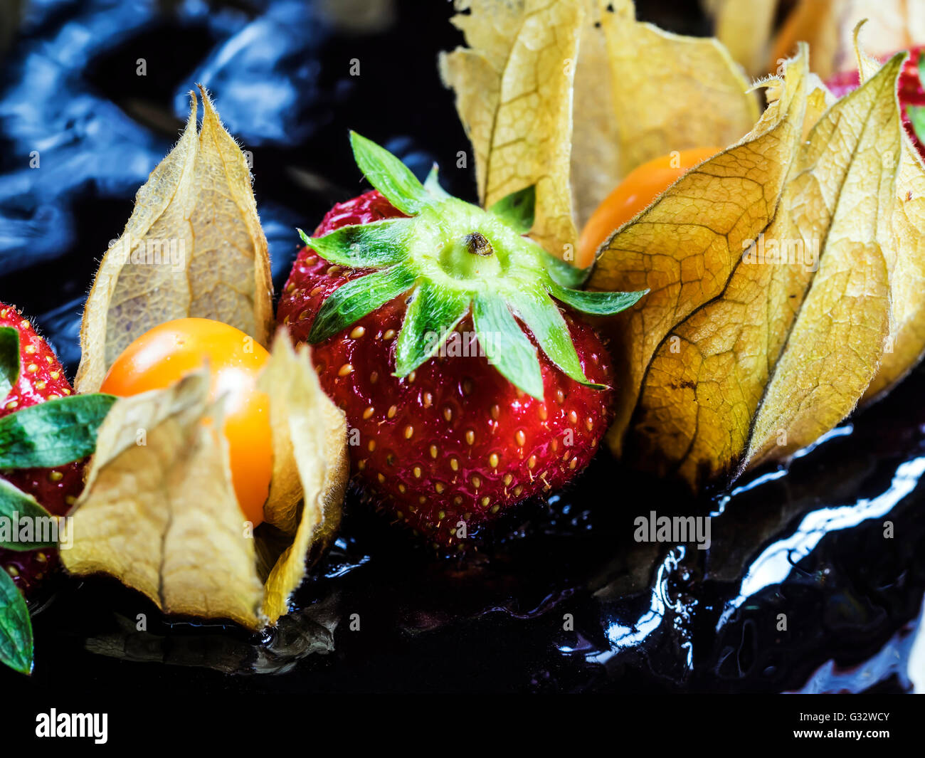 Close-up of strawberries and physalis fruit on chocolate cake Stock Photo