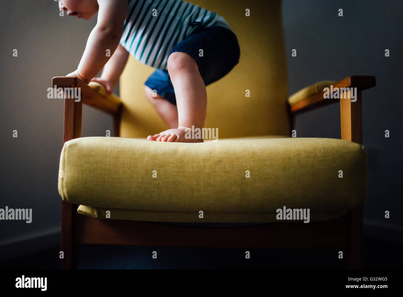 Baby boy standing on chair Stock Photo